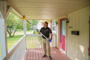 Man treating a porch during a sunny day