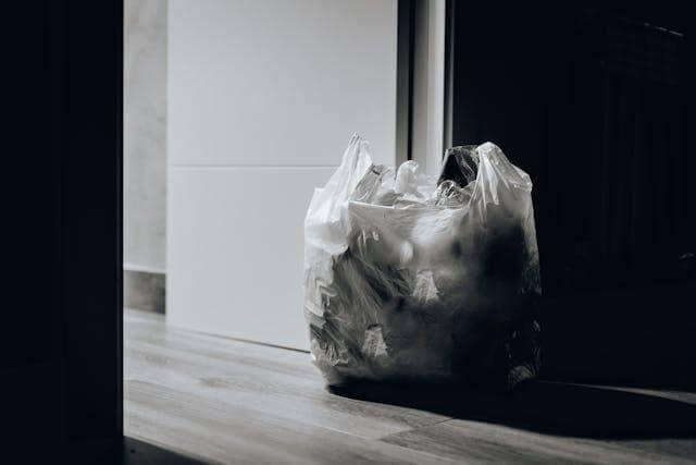 Full plastic trash bag left on the floor inside a home